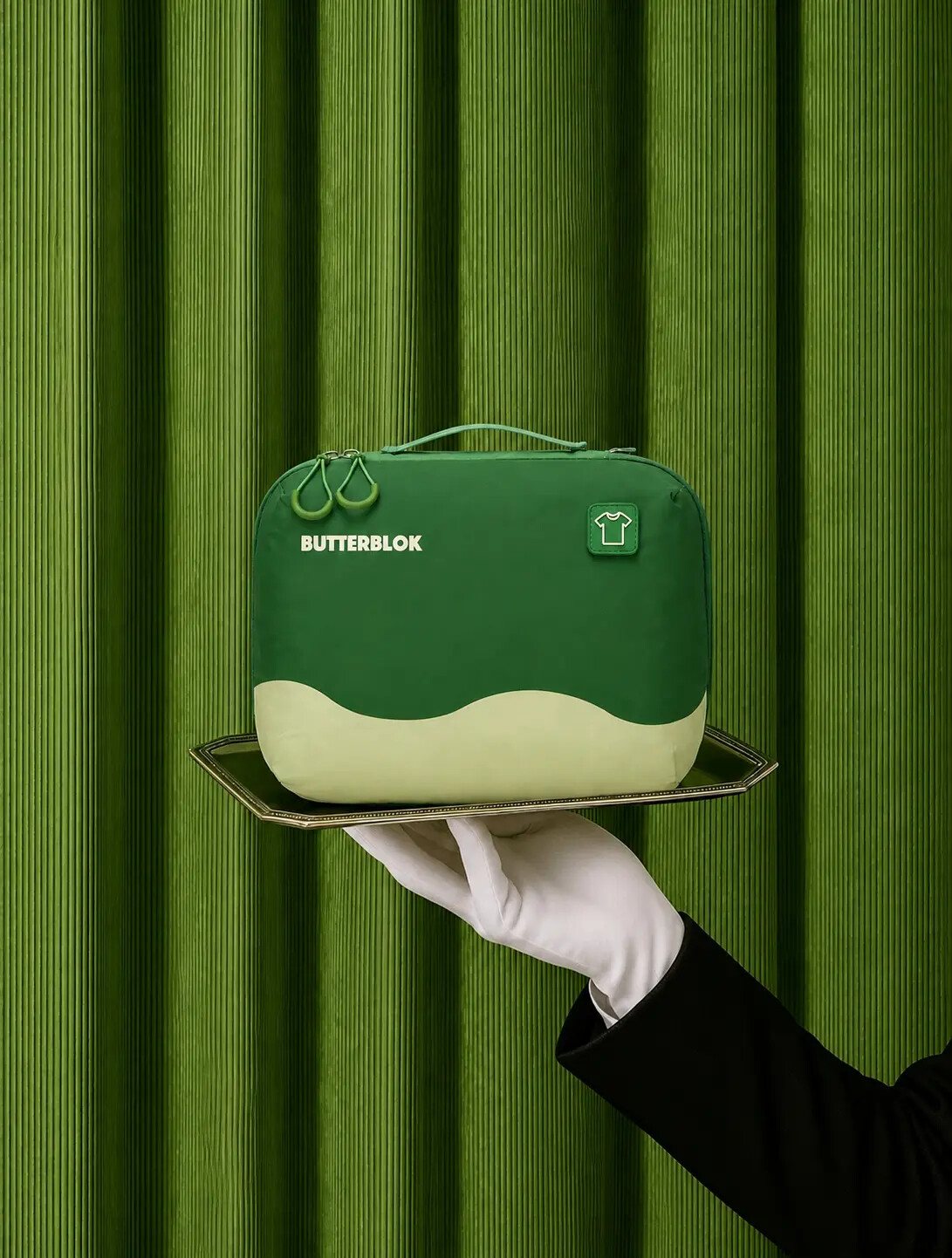 A hand presenting a forest green Butterblok cube